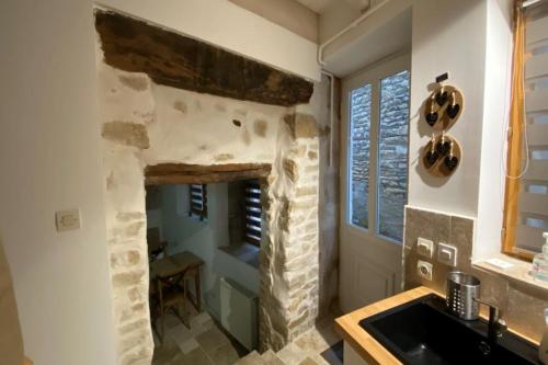 a kitchen with a stone fireplace and a sink at Le Petit Secret d'Alban in Saint-Alban-de-Roche