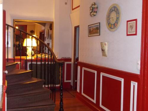 a hallway with stairs and a clock on the wall at The Originals Boutique, Hôtel d'Angleterre, Fécamp in Fécamp