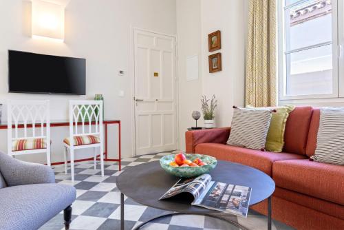 una sala de estar con sofá y un bol de fruta en una mesa en Genteel Home San Laureano, en Sevilla