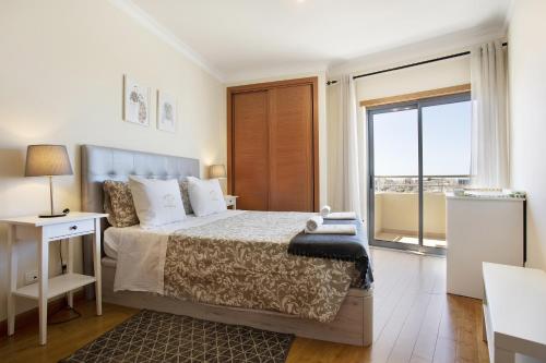 een slaapkamer met een bed en een groot raam bij Villa Rosa Apartment in Portimão
