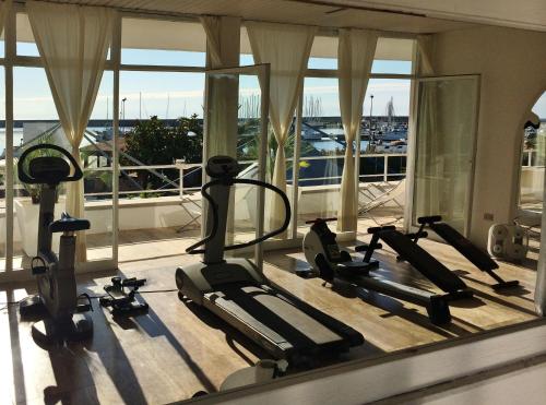 a gym with several tread machines in a room with windows at Abitare in Vacanza in La Caletta
