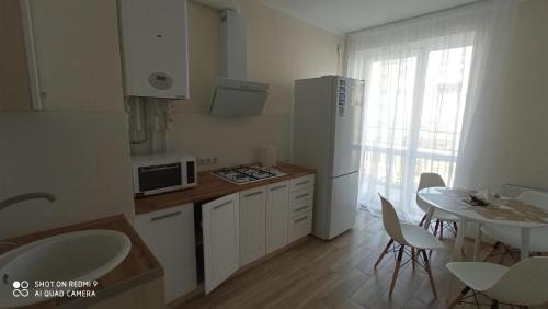ヤンタルヌイにあるАпартаменты Yantarnaya Koronaのキッチン(白い冷蔵庫、テーブル、椅子付)