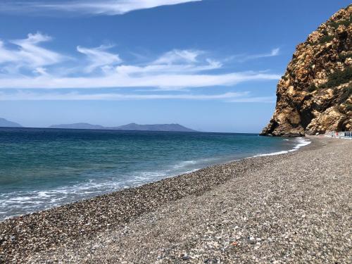 a rocky beach next to the ocean on a sunny day at mammaCristina in Patti
