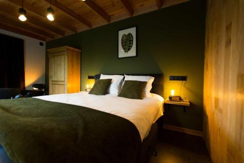a bedroom with a large bed with a green wall at B&B Fagus in Buggenhout