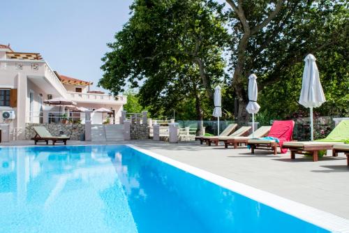 a swimming pool with lounge chairs and umbrellas at Sea and Creek in Katelios