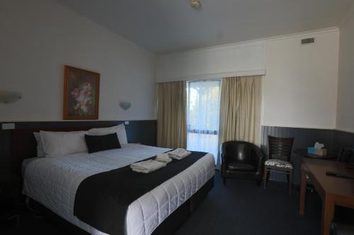 a bedroom with a bed and a desk and a chair at The Esplanade Motel in Lakes Entrance