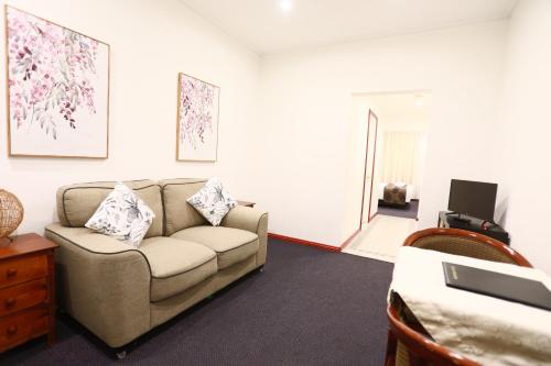 a living room with a couch and a tv at The Esplanade Motel in Lakes Entrance
