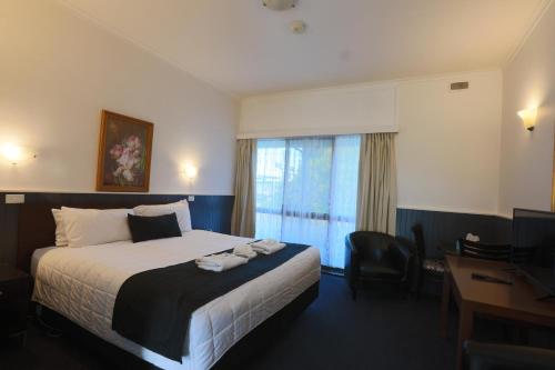 a hotel room with a bed and a desk and a window at The Esplanade Motel in Lakes Entrance