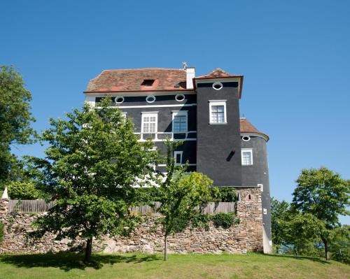a building on a stone wall with a tree at Schloß Aichberg in Eichberg