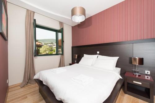 a bedroom with a large white bed and a window at Apartments Grifone Lux in Herceg-Novi