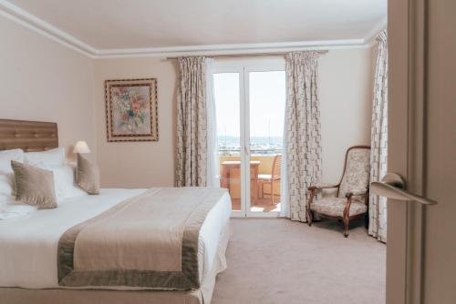 a bedroom with a bed and a chair and a window at Ermitage de l'Oasis & Spa - Cannes Mandelieu in Mandelieu-la-Napoule