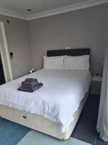 a white bed with a pile of towels on it at Private luxury Annex apartment with secure free parking in Chessington