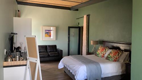 Un dormitorio con una cama y un sofá. en The Courtyard Guest House, en Clarens