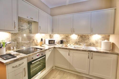 a white kitchen with white cabinets and white appliances at The View in Bowness-on-Windermere
