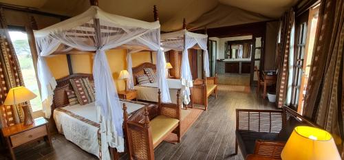 Kilima Safari Camp في أمبوسيلي: غرفة نوم بسريرين وسرير مظلة