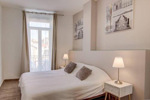 une chambre avec un lit blanc et une fenêtre dans l'établissement Palais Apartment, à Cannes