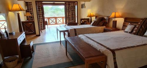 a hotel room with two beds and a balcony at Kilima Safari Camp in Amboseli