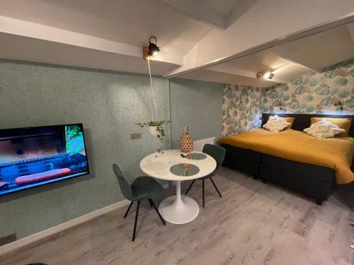 een slaapkamer met een tafel en een bed en een televisie bij Tiny House de Eikhof in Hengelo