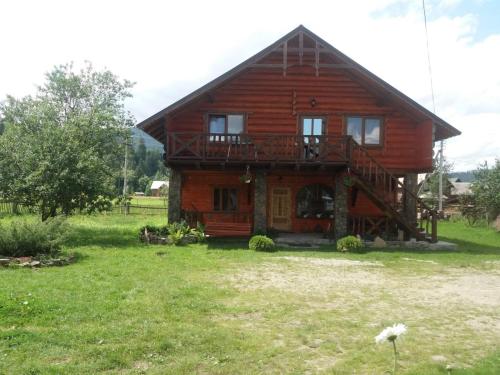 a large wooden house with a balcony and a yard at Kozarik in Mykulychyn
