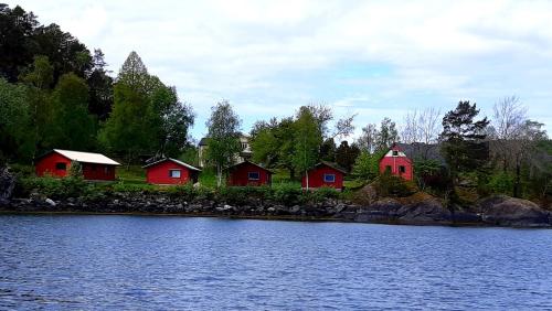 eine Reihe roter Häuser neben einem Wasserkörper in der Unterkunft Teigen Leirstad, feriehus og hytter in Eikefjord