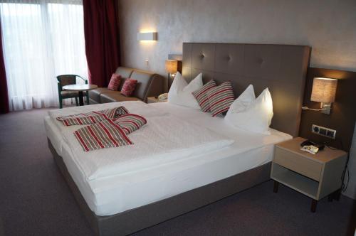 a hotel room with a large white bed with pillows at Dei Hotel Schönblick in Velden am Wörthersee