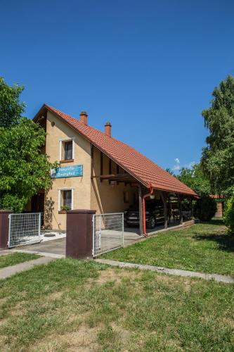 a building with a red roof and a parking lot at Aranysellő Vendégház in Abádszalók