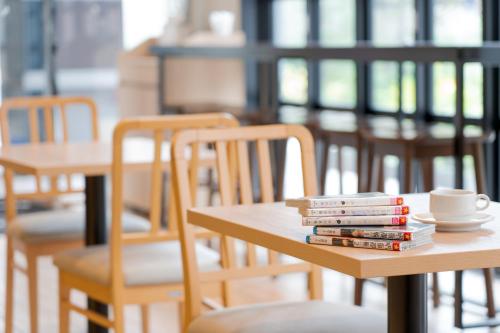 uma pilha de livros sobre uma mesa com cadeiras em Quintessa Hotel Osaka Shinsaibashi Comic & Books em Osaka