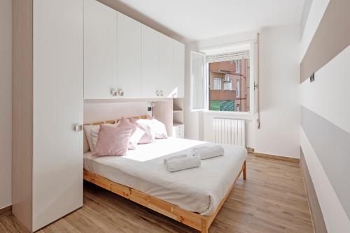 a white bedroom with a bed and a window at G&C house in Rome