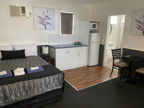 a small bedroom with a bed and a kitchen at The Esplanade Motel in Lakes Entrance