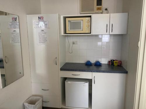 a small kitchen with white cabinets and a microwave at The Esplanade Motel in Lakes Entrance