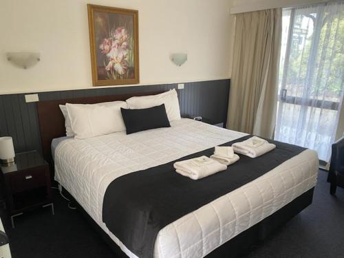 a bedroom with a large bed with two towels on it at The Esplanade Motel in Lakes Entrance