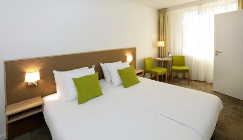 Habitación de hotel con cama blanca grande con almohadas verdes en Churchill hotel Terneuzen, en Terneuzen