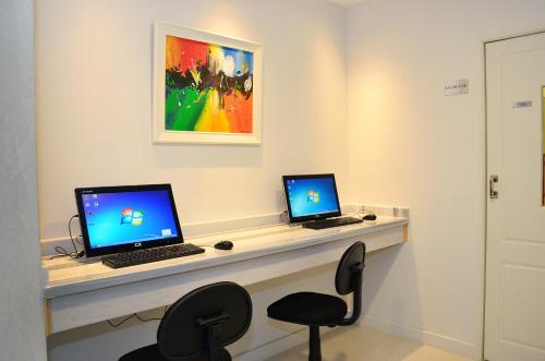 a desk with two computers on it with a chair at Le Parc Hotel & Suite in Villa María