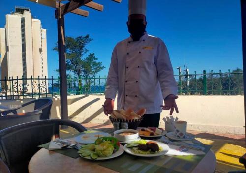 a man standing next to a table with food on it at AIFU Hotel El Montazah Alexandria in Alexandria