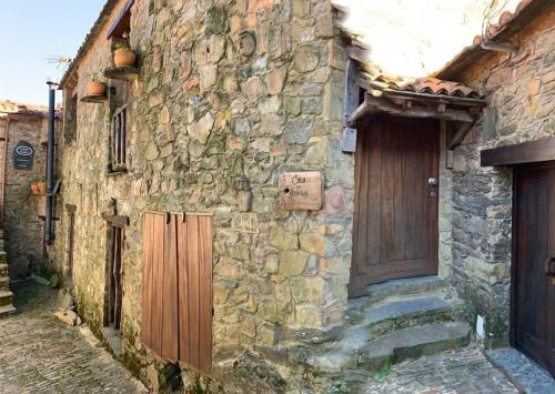 an old stone building with a wooden door and stairs at Casa das Estátuas in Gondramaz