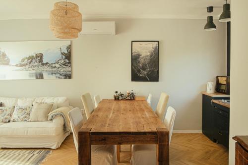 a dining room with a wooden table and a couch at Nyúlászó Vendégház és Galéria in Mád