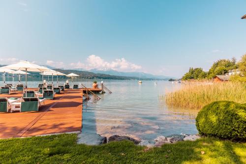 a dock with chairs and umbrellas on a lake at Hotel Schloss Seefels in P&ouml;rtschach am W&ouml;rthersee