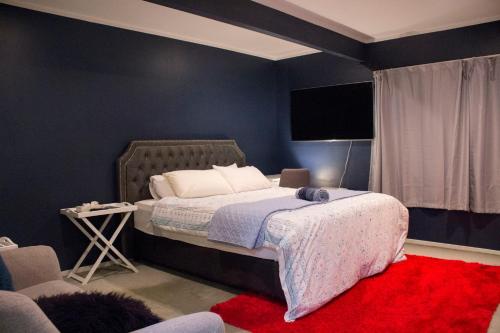a bedroom with a bed and a red rug at Lux. Room with Ensuite in Kelburn