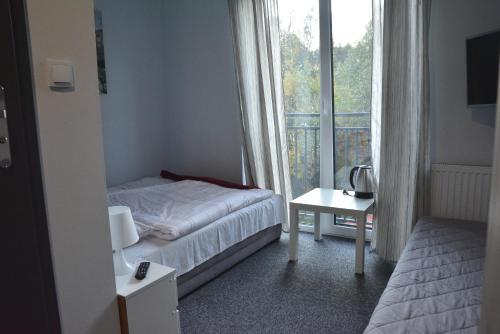 a small bedroom with a bed and a window at Dom Goscinny Skarpa in Krynica Zdrój