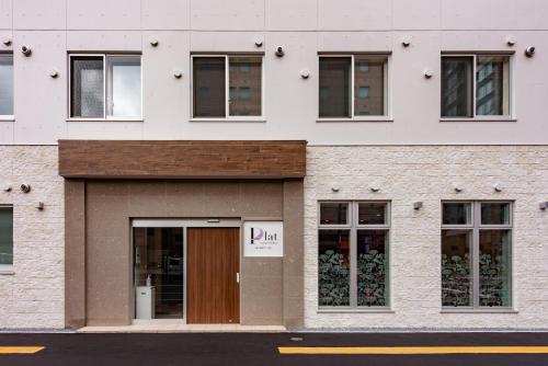 un edificio con una puerta con un cartel. en plat hostel keikyu sapporo sky en Sapporo