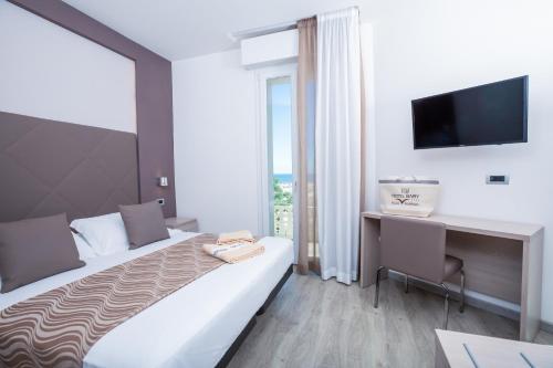 Habitación de hotel con cama, escritorio y TV. en Hotel Baby en Rímini