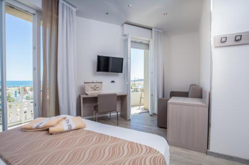 a bedroom with a bed and a desk and a television at Hotel Baby in Rimini