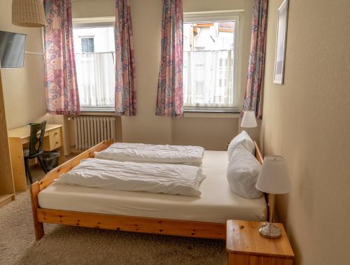 two beds in a room with two windows at Südhotel in Paderborn