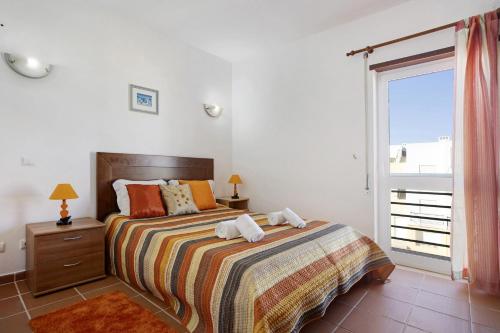 een slaapkamer met een bed en een groot raam bij Apartamento Meia Praia in Lagos