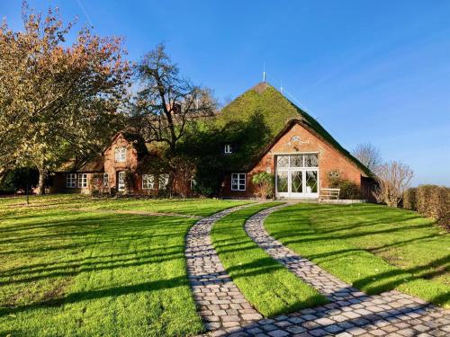 a house with a cobblestone path in front of it at Haubarg alte Strandvogtei in Westerhever