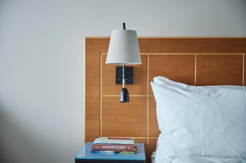 a bed with a lamp on a table next to a bed at Hotel Klubben in Tønsberg