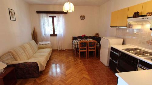 a living room with a couch and a table in a kitchen at Apartments Tonica in Malinska