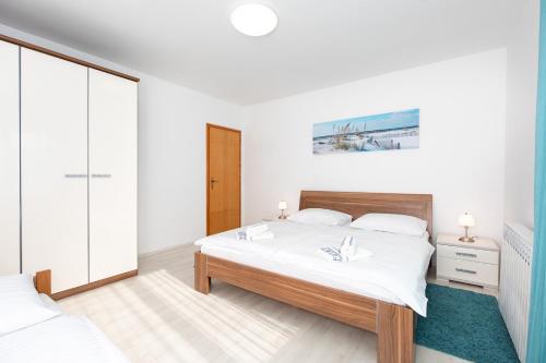 a bedroom with a large bed with white sheets at Apartments Tonica in Malinska