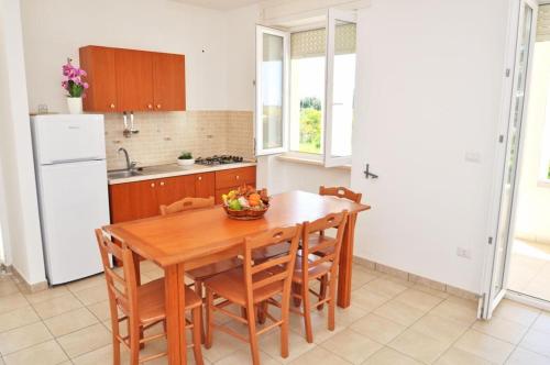 a kitchen with a wooden table with chairs and a bowl of fruit at Residence Punta Pizzo in Marina di Mancaversa