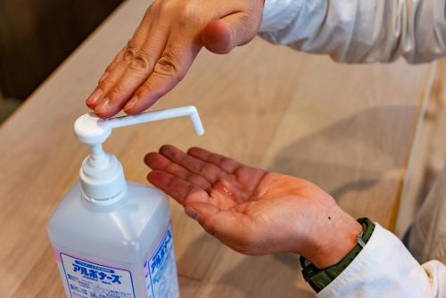 a person is reaching for a bottle of hand sanitizer at plat hostel keikyu sapporo sky in Sapporo